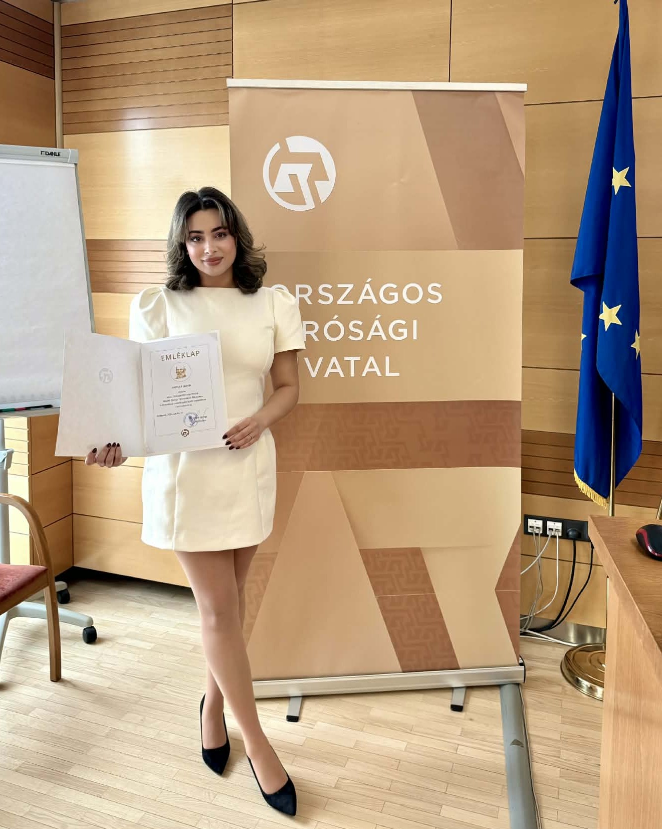 A képen Mutlak Jázmin látható a KRE ÁJK V. évfolyamos hallgatója ahogyan tartja az oklevelét a Mailáth György Tudományos Pályázat díjátadóján.